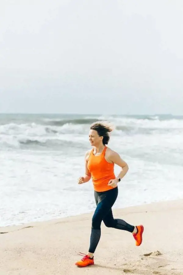 Woman in an orange top running on the beach
