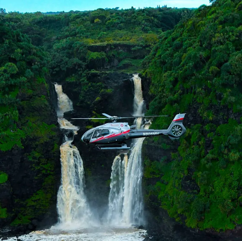 A  passenger chopper from Maverrick Helicopter flying by an amazing waterfalls in Maui
