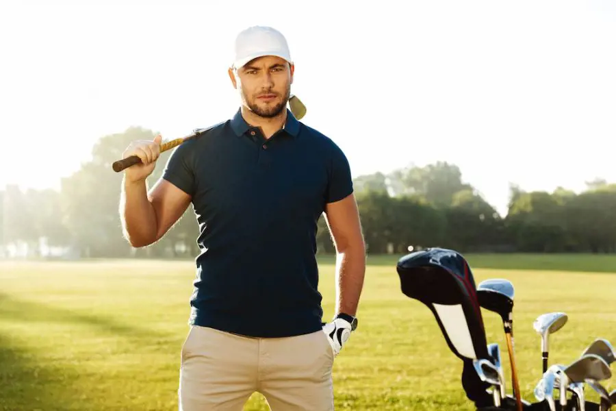 A handsome confident male golfer striking a pose with his golfing gears.