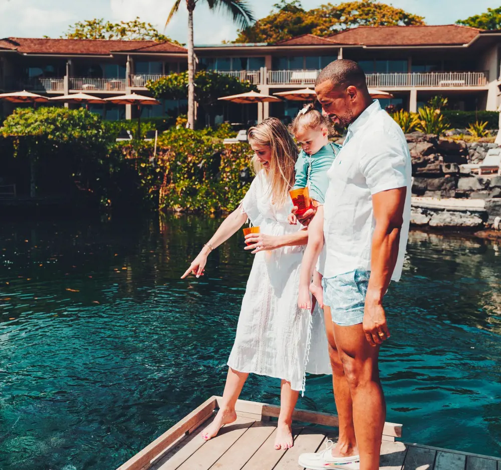A family watching fishes in the King's Pond at Four Seasons Resort Hualalai