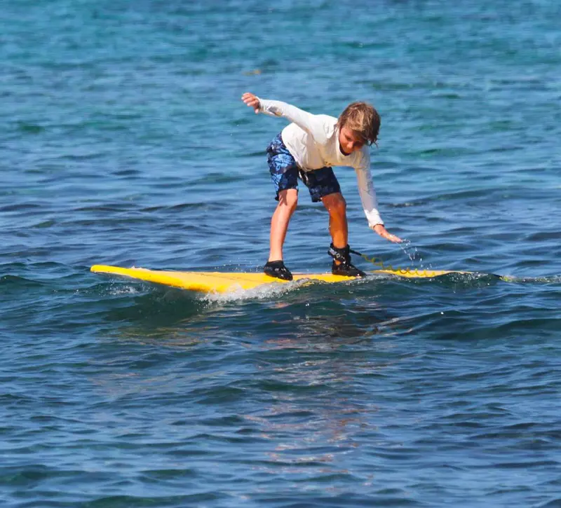 A kid learning surfing at Kahaluu Bay in Hawaii
