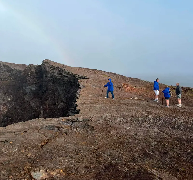Hikers crawling up to the mouth of a volcanic crater to observe the dormant volcano