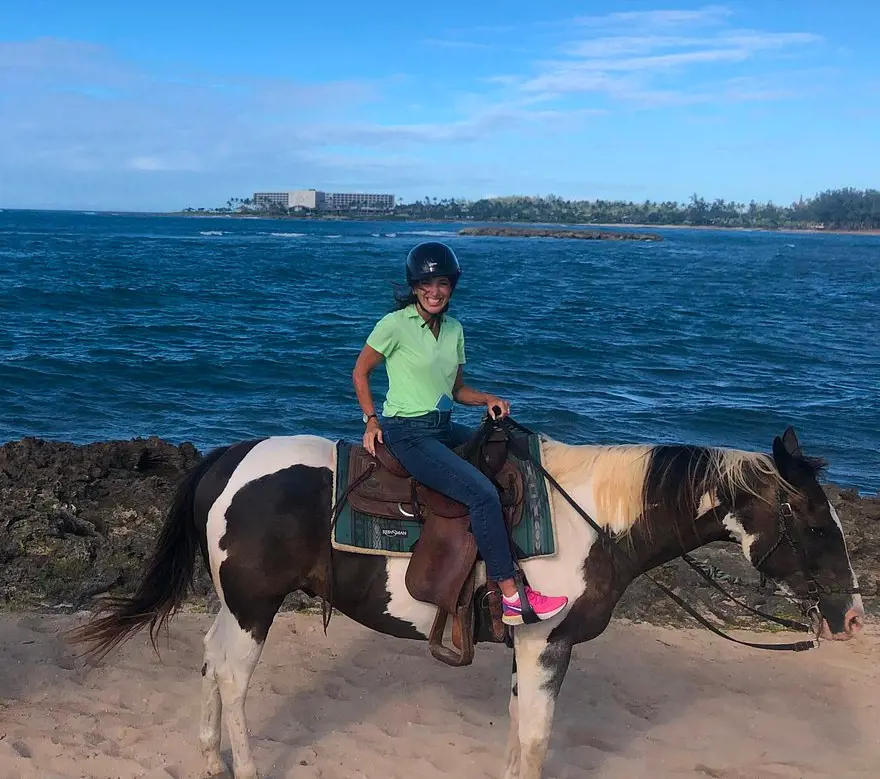 A tourist joyfully riding a horse by the beach