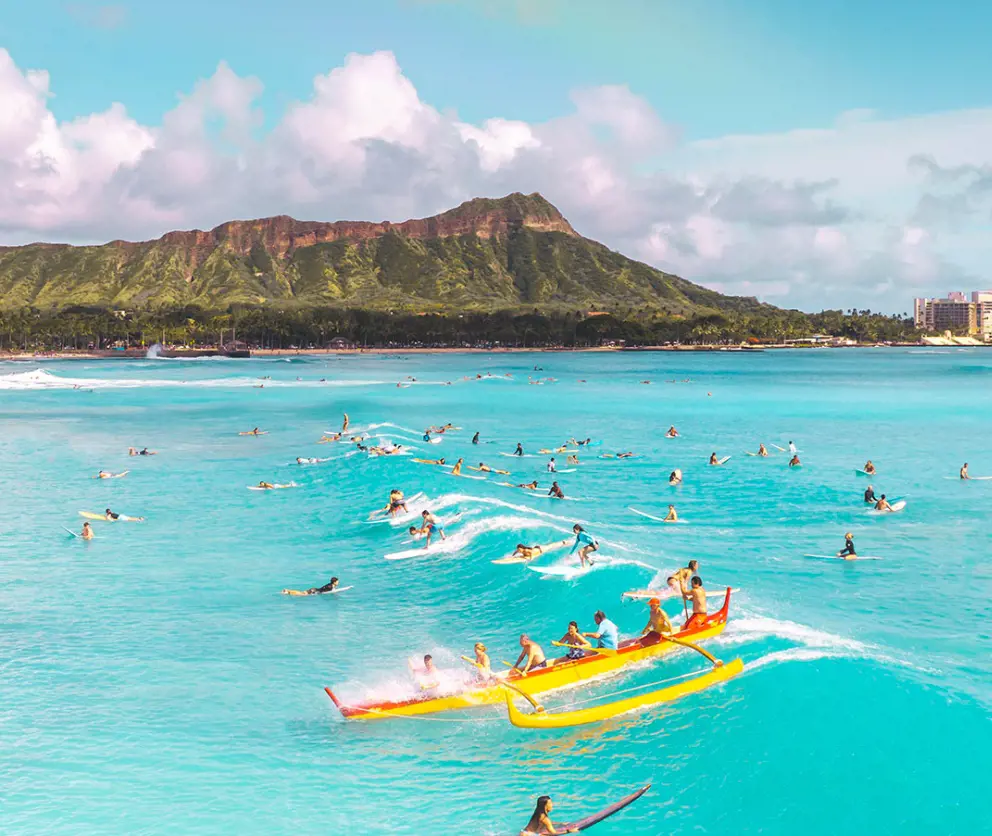 People enjoying surfing and paddle boarding in the Pacific with Diamond Head Mountain in the background