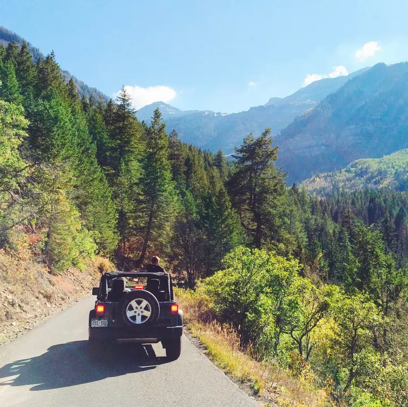Travelers driving a rented jeep on a rural road with beautiful scenery
