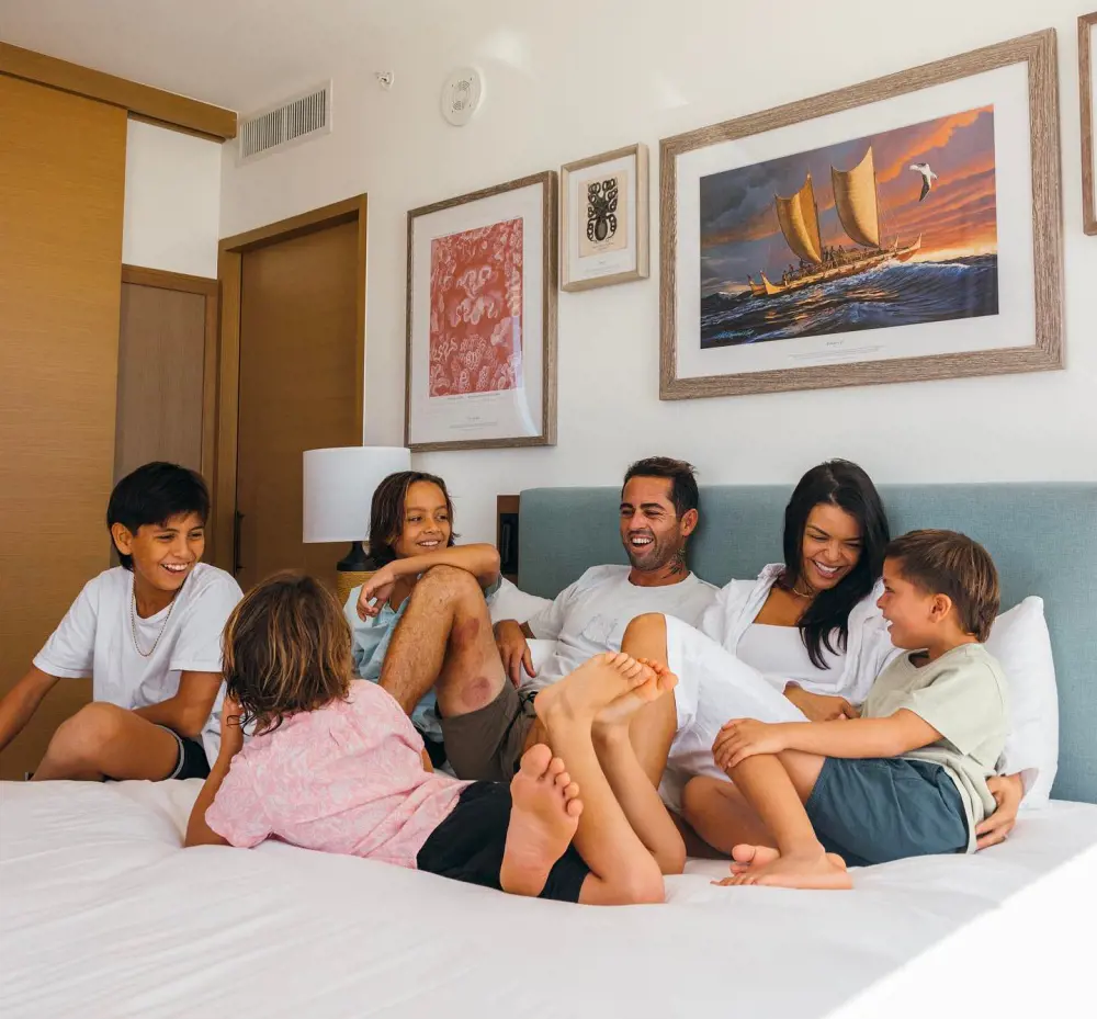 A couple and their children having some quality time together in a cozy room at Outrigger Reef Waikiki Beach Resort