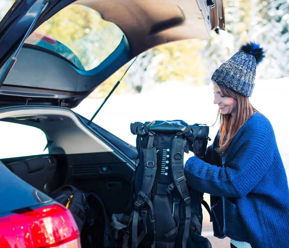 A traveler loading her luggage in the car trunk before heading out for a drive
