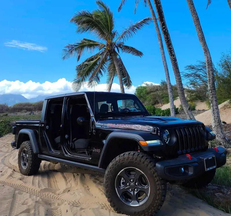 A Jeep Wrangler from Cruisin' Maui Rent-A-Car parked on the beach