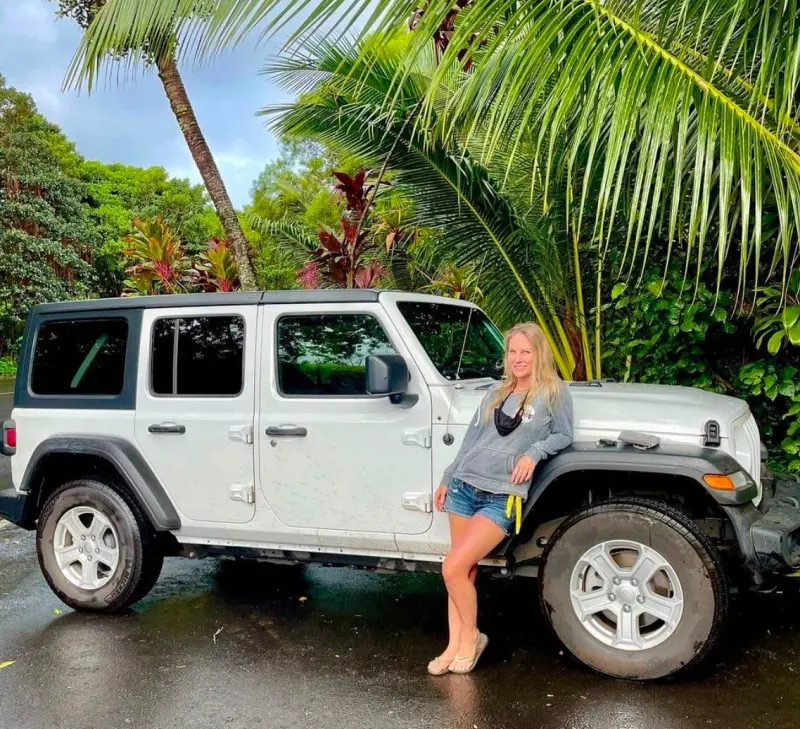 A traveler posing beside the Jeep Wrangler from Thrifty Car Rental