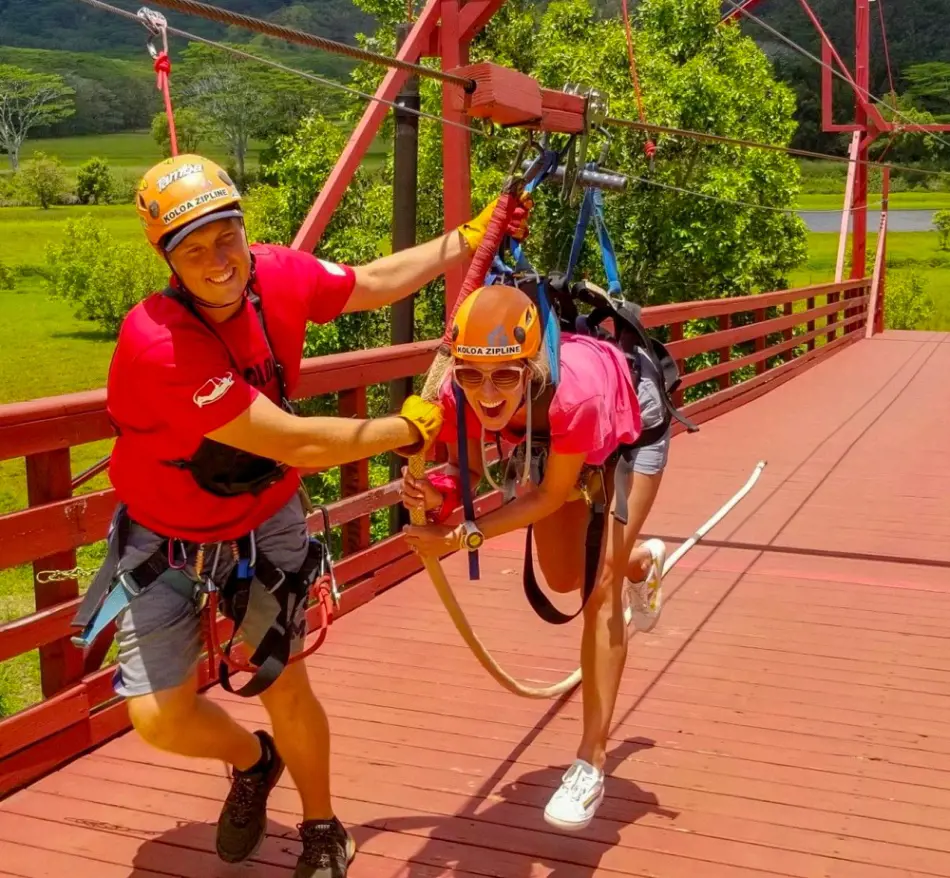 A zipline guide preparing a tourist for zipline adventure at Koloa Zipline in Kauai