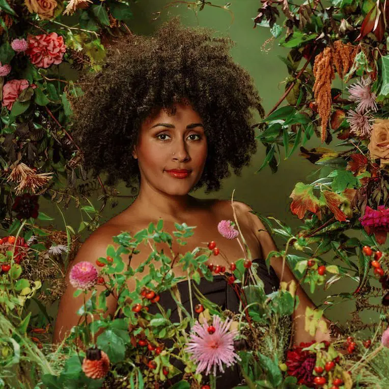 Irie poses for a photoshoot in a setting decorated with colorful flowers in 2021