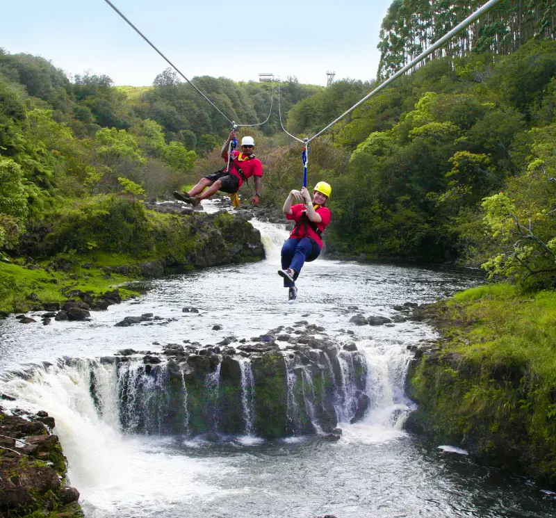 Visitors enjoy ziplining over the river in the Big Island, Hawaii