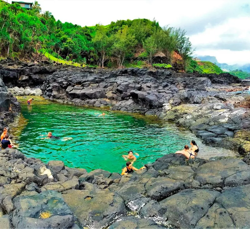 People taking a dip and cooling off at Queen's Bath in Princeville, Kauai