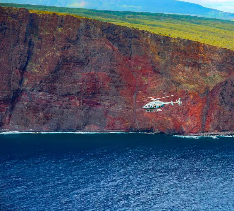 A passenger chopper from Paradise Helicopters flying past the Kalaupapa cliffs in Molokai