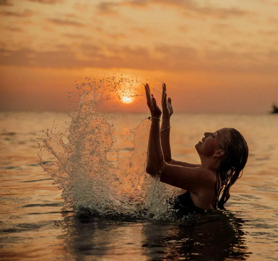 A candid shot of a lady enjoying in the calm ocean waters during sunset
