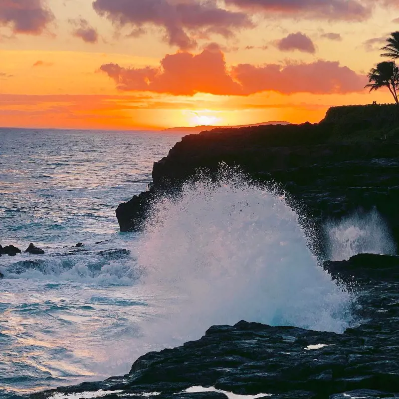 A beautiful shot of the waves crashing against the cliffs at Poipu Beach during sunset