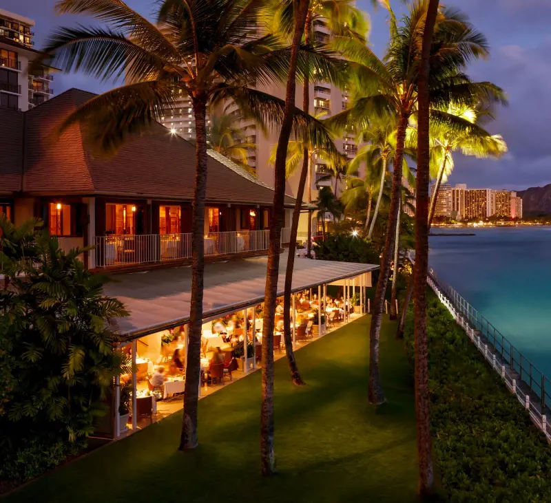 A beautiful evening shot of the oceanfront Orchids Restaurant at Halekulani Hotel