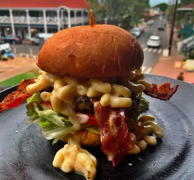 The Mac & Cheeseburger with homemade white cheddar and smoked Gouda prepared at Cool Cat Cafe Maui to cheer you up on a gloomy day
